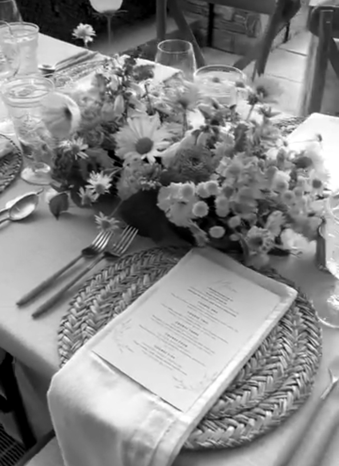 A table setting with wildflowers, a woven charger and a printed menu
