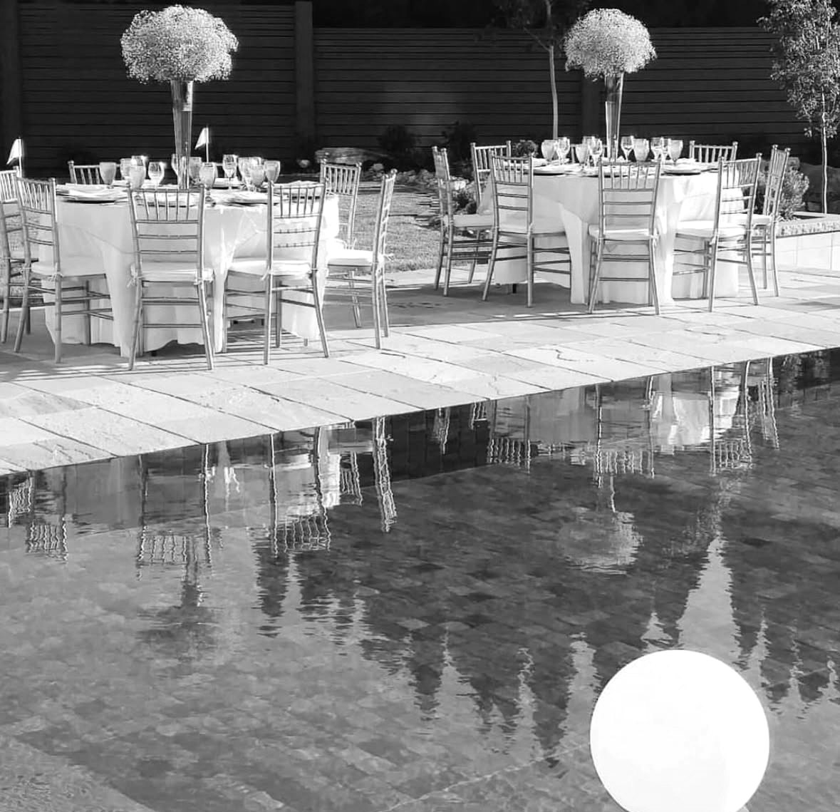 Poolside dinner tables with gold chairs and tall floral centrepieces